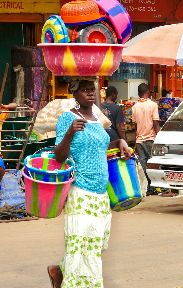gallery-2 Colorful buckets carried by a woman in a bustling Sierra Leone market.