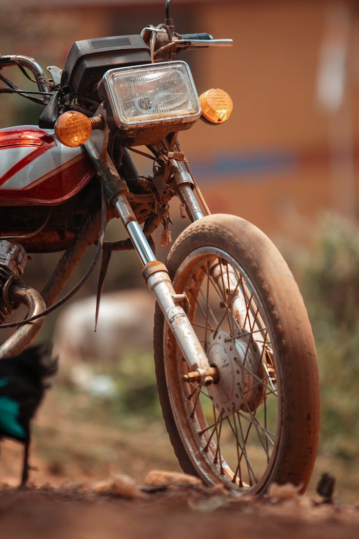 services-img Detailed view of a vintage motorcycle with dirt marks, captured on a rustic outdoor path.
