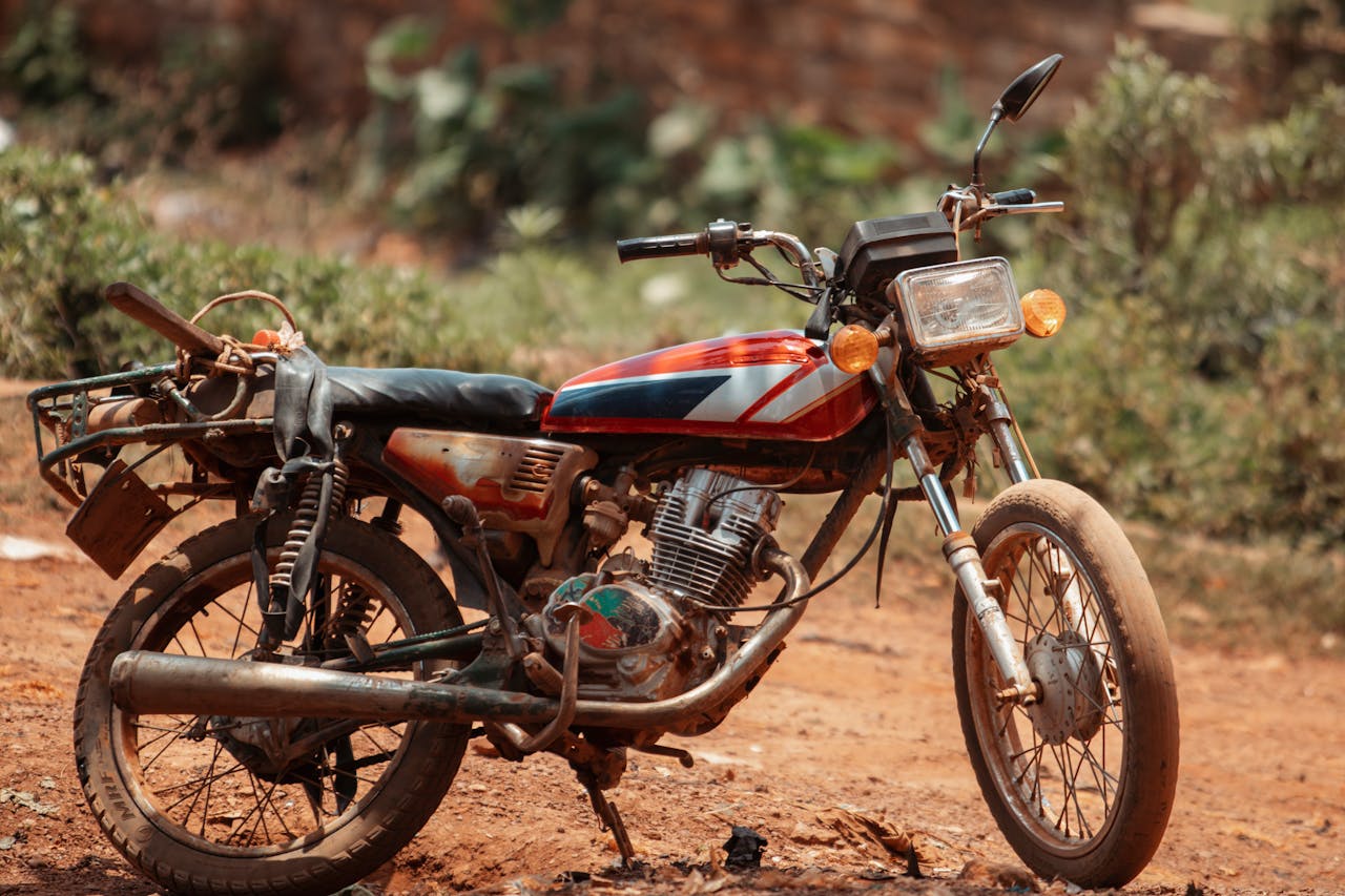 services-01 Classic motorbike parked on a rural dirt path, evoking nostalgia.